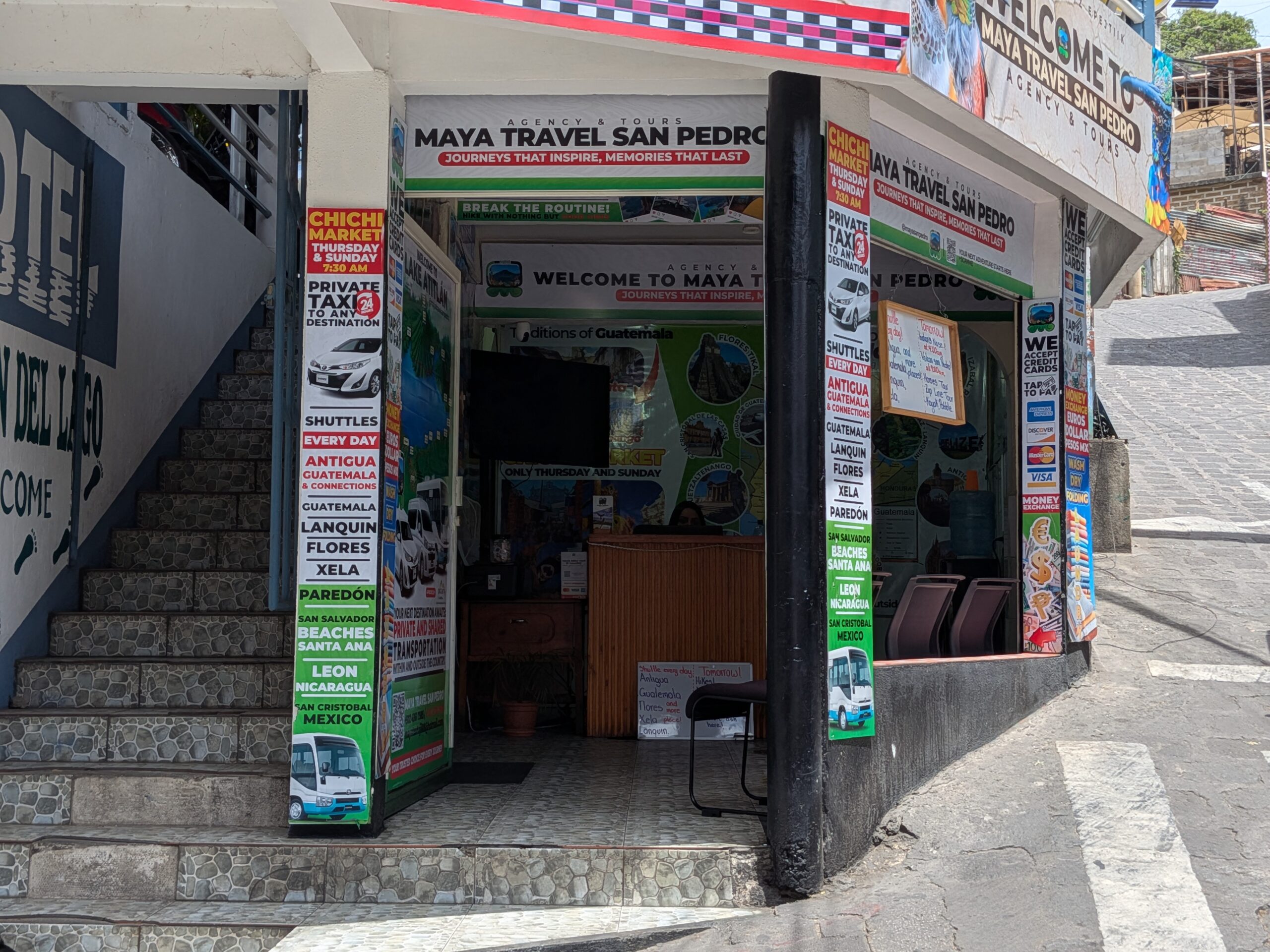 位於瓜地馬拉阿蒂特蘭湖畔聖佩德羅（San Pedro La Laguna）的 Maya Travel San Pedro 旅行社門口，招牌上清楚列出前往墨西哥聖克里斯托瓦爾（San Cristobal）的巴士路線與時刻表。