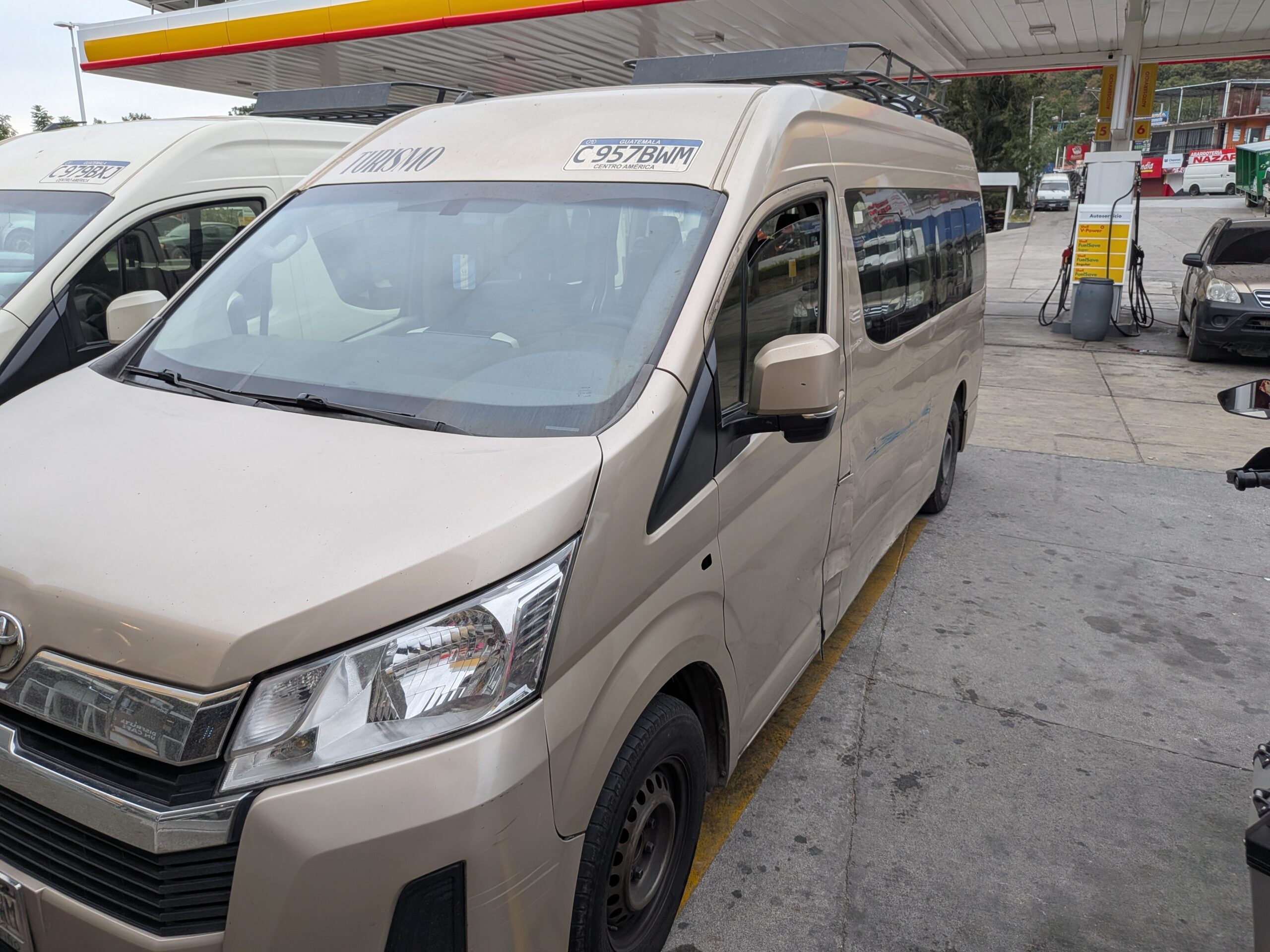 在瓜地馬拉路段實際搭乘的跨國接駁廂型車（Shuttle），車頂配有行李架，攝於中途停靠的加油站，準備載運乘客前往邊境。